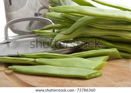 String beans on a board with cooking pan