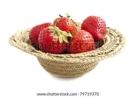 Straw hat filled with strawberries isolated over white