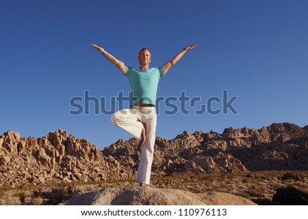 Man outdoors in the yoga pose Vrasana or Tree Pose.