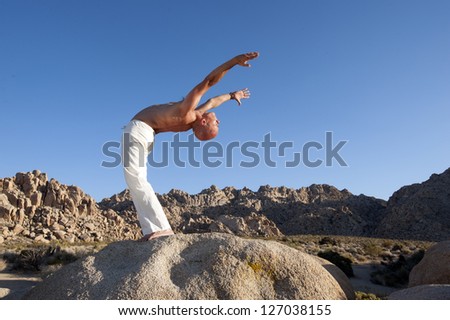 Man in ecstatic yoga backbend outdoors in the desert.