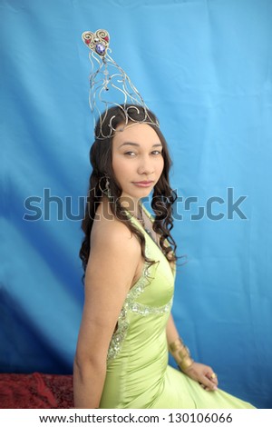 Portrait of a strong beautiful young woman wearing a green gown and a heart crown.