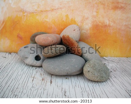 River stones lazily grouped with a hand painted yellow backdrop.