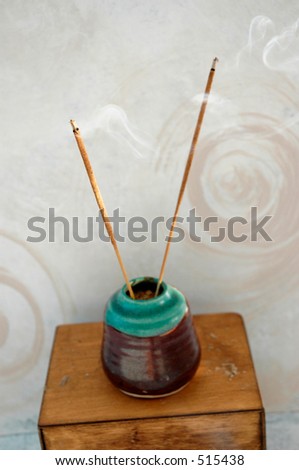 Incense burning next to a spiral painted wall. Shallow depth of field, focus on the foreground stick.