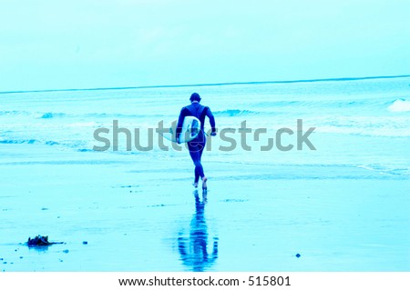 Soft focus motion blurred blue toned images of surfers. Surfer running with board.
