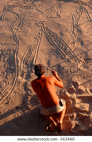 Man drawing angels in the sand on the beach.