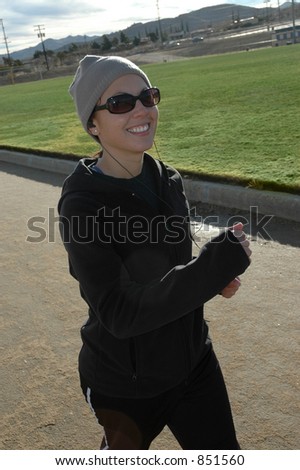 Young woman smiling as she power walks on track.