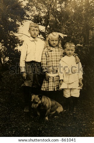 Three siblings in a vintage garden portrait with the family dog.  Original Circa 1909 print has scratches, artifacts, fading and solarization qualities.