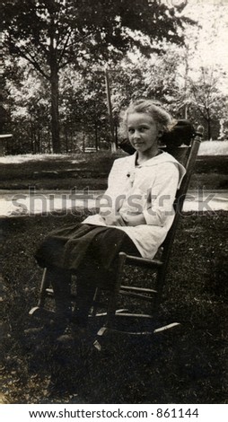 Vintage portrait of a little girl sitting on a rocking chair.  Original Circa 1910 print has scratches, artifacts, fading and solarization qualities.