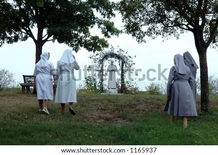 Salesian nuns walk up a hill to visit the staute of Don Bosco.
