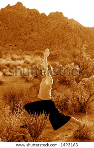 Toned black and white image of woman practicing yoga in the desert.