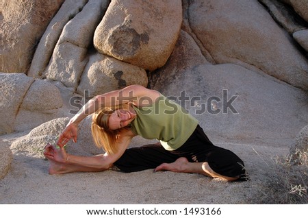 Woman in a seated yoga stretch in the boulders.