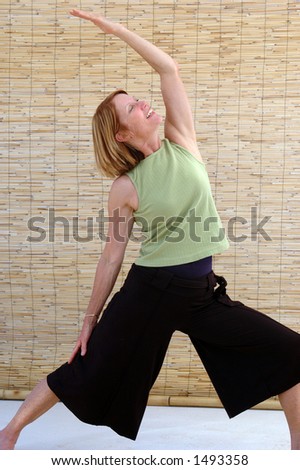 Senior woman going into the reverse warrior yoga pose.