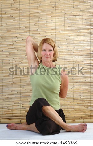 Senior woman seated in the Cow-Face gomukha-asana yoga posture.