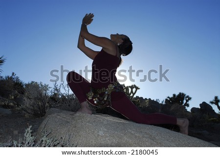 Semi silhouette of Woman in yoga pose outdoors in the desert.