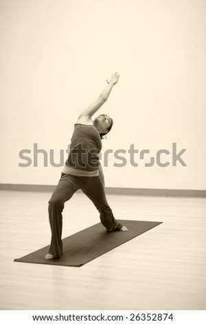 Asian woman in reverse warrior yoga pose. Sepia toned.