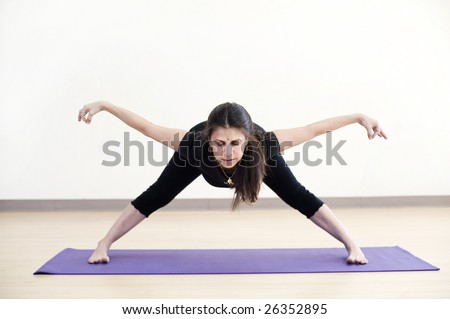 Middle aged hispanic woman in a bowing yoga pose with arms like wings.