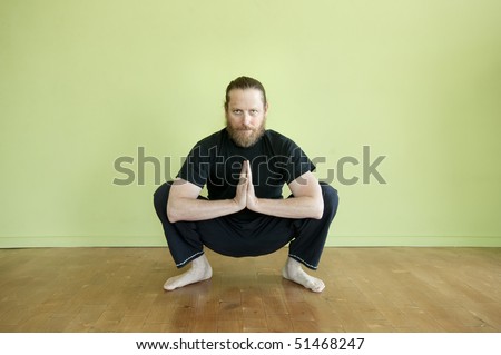 Middle aged man in yoga squat in prayer pose.