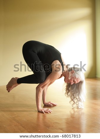 Mature woman in the yoga posture Bakasana or crow pose.