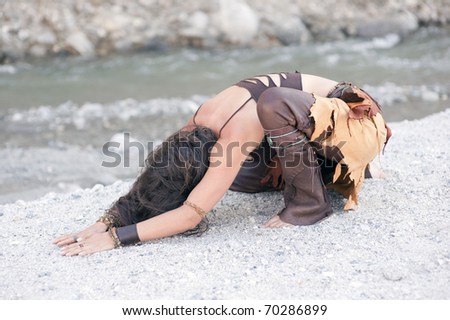 Earth Day. Wild woman bowing to the earth next to a river.