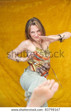 Playful adult woman making a karate kick.