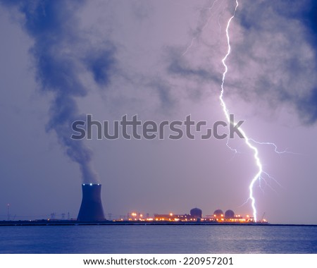 A contrast photograph of the power of mother nature and man-made energy; A lightning bolt striking the water in take area of a nuclear power plant.