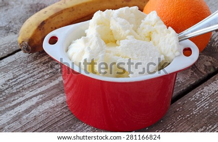 white ice cream in red bowl with fruits on background
