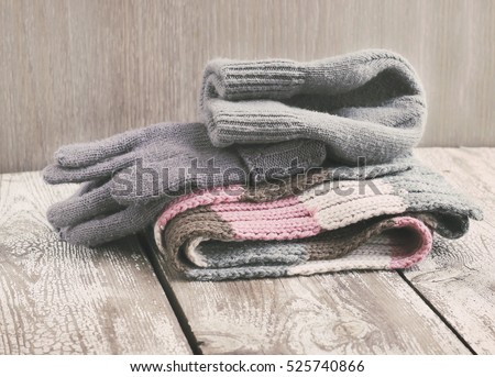 Warm winter knitted clothes - hat, scarf, gloves on a wooden background, female, selective focus, vintage toning