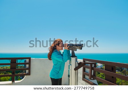 Girl brown-haired woman looks through a telescope on the Observatory and smiles