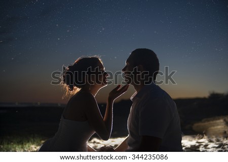 Silhouette of a young couple on the background of the night sky