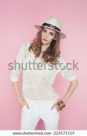 Beautiful woman in hat and white clothes and hat posing on pink background