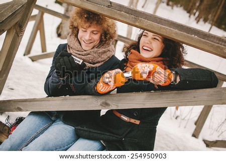 Young happy hipster couple playing harmonica together in winter outdoors