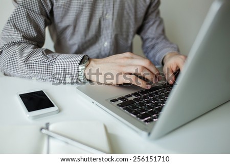 Business man typing on laptop with smartphone on the table