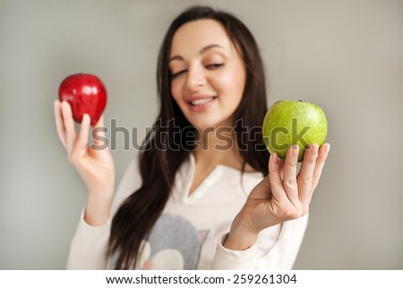 Young woman holds two apples green and red smiling