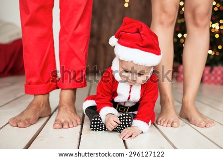 Baby in santa suit with family indoor with Xmas tree