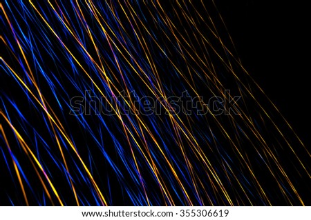 Abstract multicolored light beams in motion, light painting on a black background