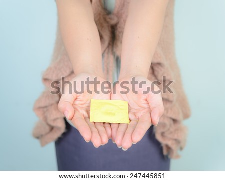 hand woman showing a condom , Focus on the condom in the foreground