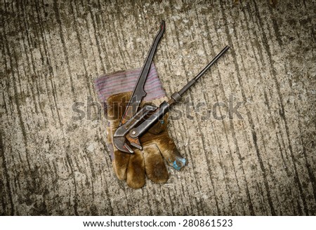 Still life with old locking plier and old glove on grunge background