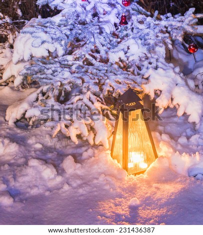 Lamp fire in snow near the Christmas tree