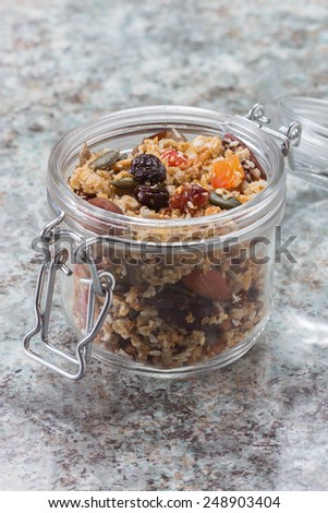 Quinoa granola in open glass jar on marble stone background