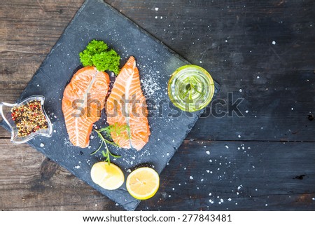 Red fish medallions on black rustic wooden background, top view, cooking background