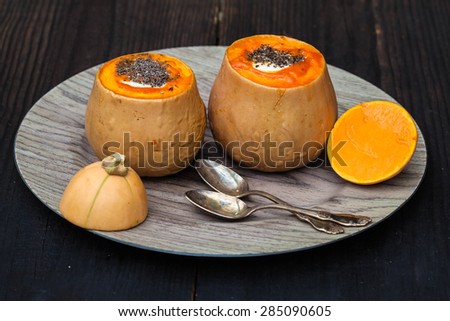 Baked squash with cheese, rice and chia seeds on wooden plate, black wooden background, selective focus
