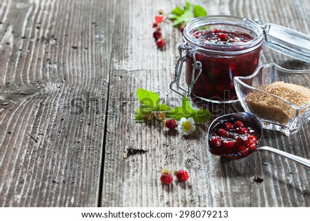 Forest strawberry jam in a jar on rustic wooden background