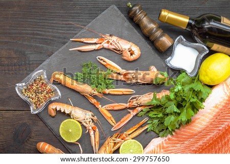 Delicious fresh fish and shrimps on dark vintage background. Fish and shrimps with aromatic herbs, spices and vegetables - healthy food, diet or cooking concept