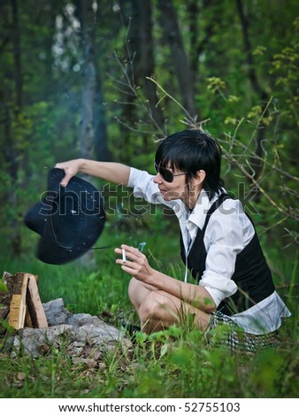 Woman like cowgirl in the forest near a campfire - stylization