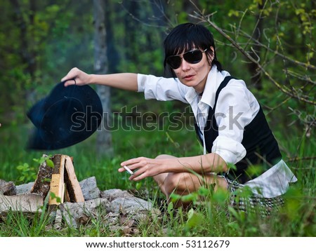 Woman like cowgirl in the forest near a campfire - stylization