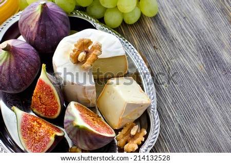 Cheese with fruits on a tray, selective focus, sample text