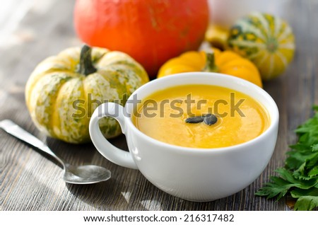 Pumpkin soup with pumpkins on wooden background