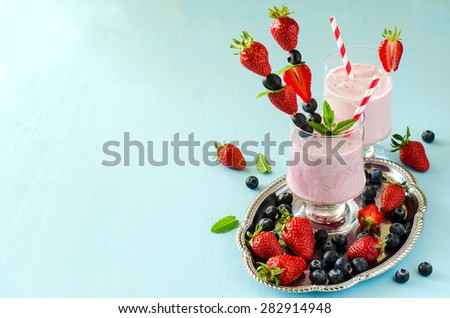 Fresh healthy strawberry and blueberry pink smoothie, summer refreshing drink, milk shake with ripe berries and yogurt  lots of copy space
