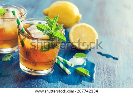 Fresh cold iced tea, lemon and mint cocktail, refreshing summer drink copy space background