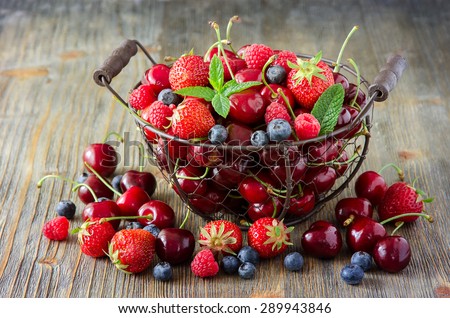 Fresh ripe berries mix, cherries, raspberries, blueberries in vintage basket, summer harvest concept, vitamins, healthy food, vegan ingredients